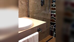 Une salle de bain avec un lavabo rond, une serviette suspendue à un porte-serviettes et un espace douche.