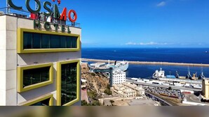 Un hôtel appelé « COSIMO HOTEL », offrant une vue sur l’océan et situé à proximité d’un quai où est amarré un navire de croisière.