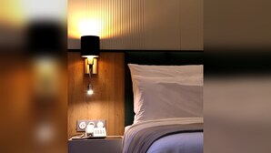 Une chambre d’hôtel avec un lit, une table de chevet avec une lampe et une prise de courant fixée au mur.