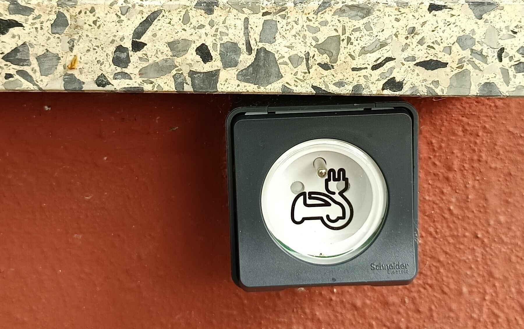 A button with a hand symbol on a textured surface.