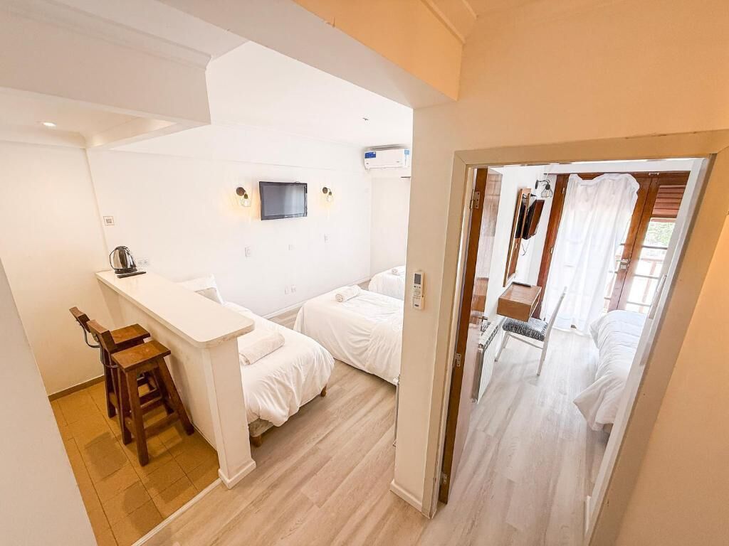 Habitación con dos camas, una kitchenette pequeña, un televisor y una puerta que da a otra habitación.