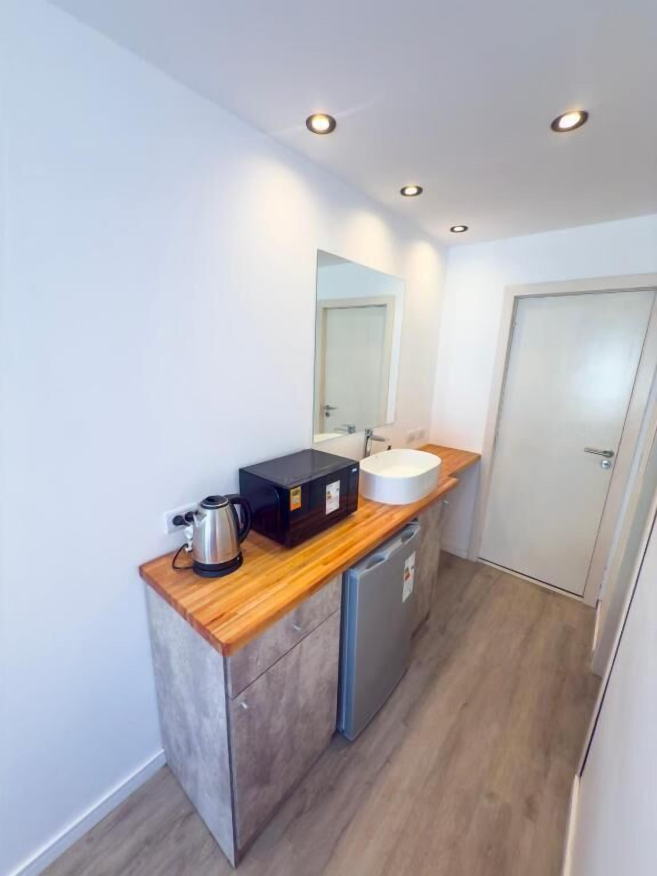 A compact bathroom with a wooden countertop, a sink, a mirror, and a door.
