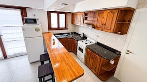 Una cocina compacta con armarios de madera, microondas, estufa y mostrador tipo barra.