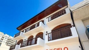 Un edificio de varios pisos con un llamativo letrero 'MAR Y CIELO', balcones y un área de entrada techada.