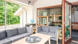 Una sala de estar moderna con un sofá gris, una mesa de centro de madera y un puerta de cristal que da a un balcón.
