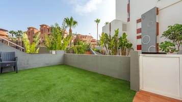 A courtyard with artificial grass, a bench, and a white wall with circular patterns.