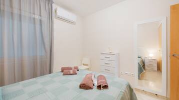 Un dormitorio con cama, cómoda, espejo y aire acondicionado.