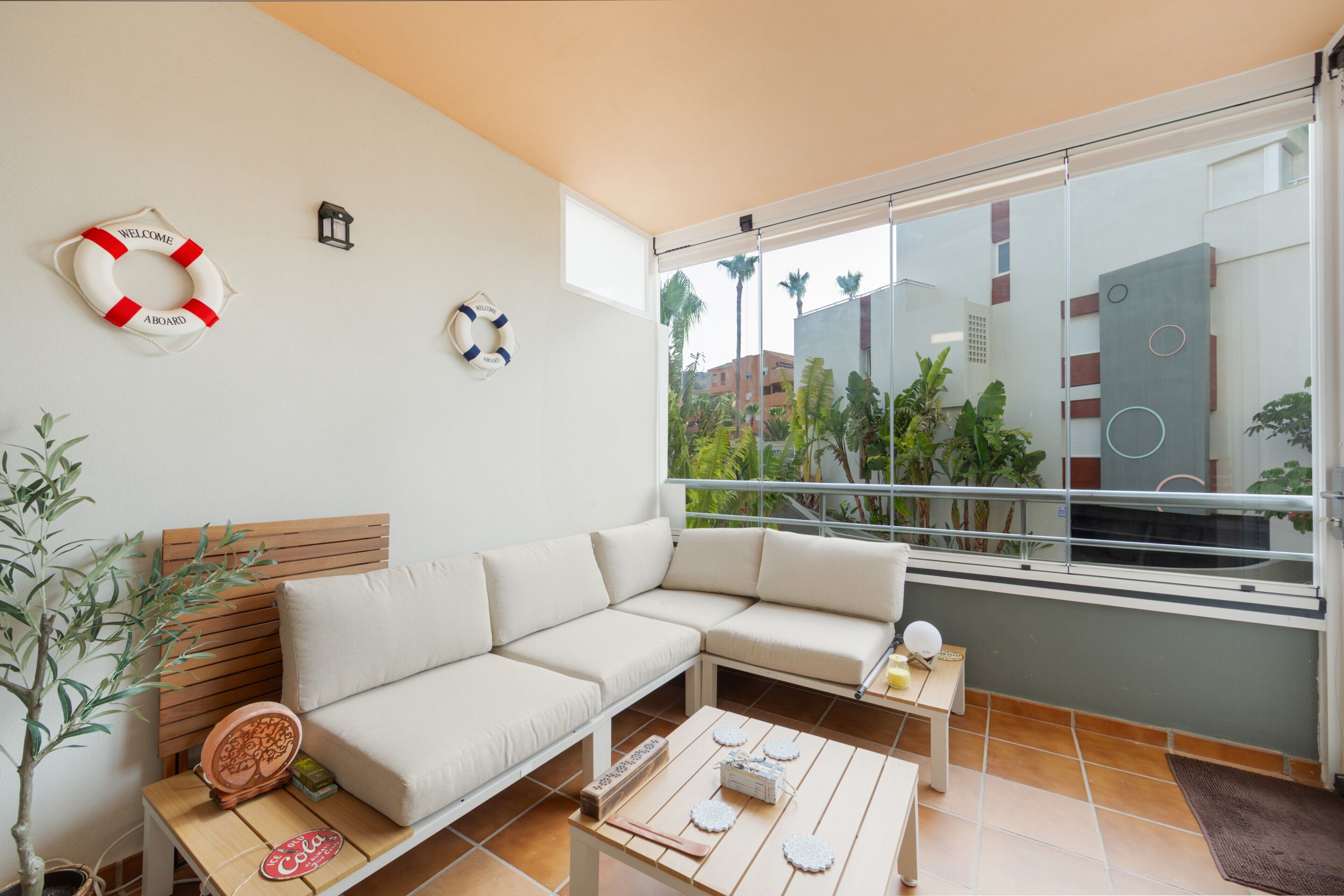 Una sala de estar moderna con un sofá, una mesa de centro, una mesita con objetos decorativos y vistas a la ciudad a través de amplias ventanas.