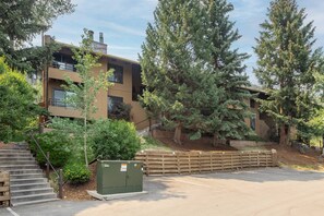 A multi-story building with a staircase leading to a balcony, surrounded by trees and a fenced parking area. - Spacious Retreat in Snowmass Village! Gas Fireplace, HT, on Free Shuttle (Snowmass Village)