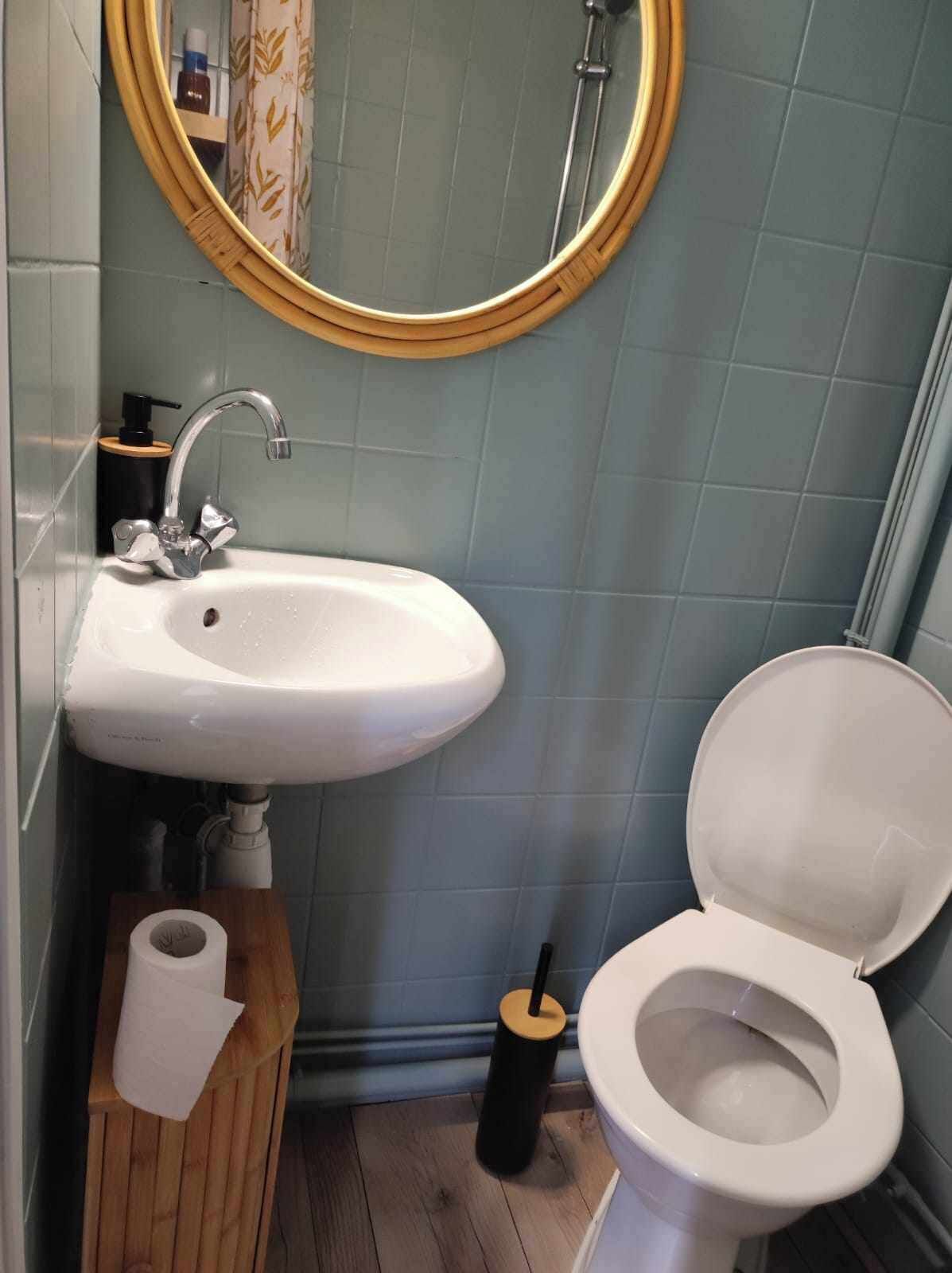 Een badkamer met een witte wastafel, toilet en een houten opbergmeubel.
