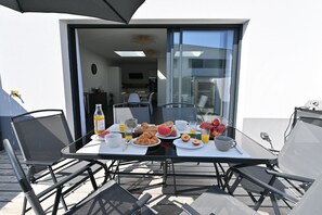A dining table with breakfast items and chairs, a glass door leading to a kitchen, and a view of the sky. - Villa in Pornichet – beach within walking distance, terrace, quiet and bright, Bonne Source (Pornichet)