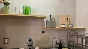 Une cuisine équipée d’une machine à café, d’un évier, d’une étagère avec un range-couteaux et d’une bouteille d’huile d’olive.