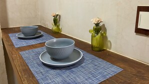 Une table de salle à manger en bois, avec deux bols et deux vases verts ornés de fleurs.