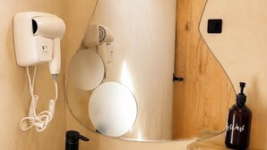 Une salle de bain avec un lavabo en forme de bol en bois, un miroir avec un cadre en bois, un sèche-cheveux et un distributeur de savon.