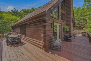 Eine Blockhütte mit einer Terrasse, einem Tisch mit Stühlen und einer Bank.