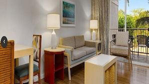 Ein Wohnzimmer mit einer Couch, zwei Beistelltischen, einem Sessel, einem kleinen Tisch und einem Bild an der Wand.