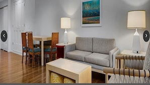 Ein Wohnzimmer mit einer Couch, zwei Sesseln, einem Tisch und zwei Lampen.