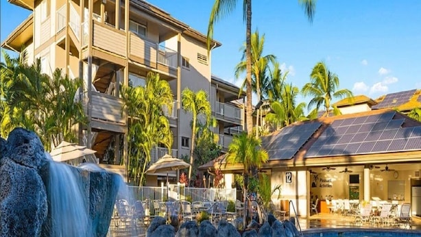 Ein Hotel mit Pool, Palmen und einem Wasserfall.