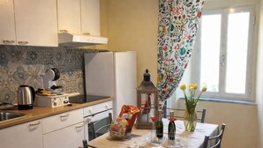 Een keuken met een eettafel voor vier personen, een waterkoker, een broodrooster en een raam met gordijnen.