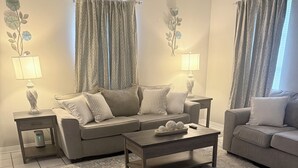 A living room with a sofa, two side tables, a coffee table, patterned rug, and curtains. - Home Sweet Home Nearby Beach & MS Gulf Coast! (Grand Bay)