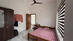 A bedroom with a bed, a desk, a chair, a wardrobe, and a ceiling fan. - Room-tiny Horizon Retreat (Payyanur)