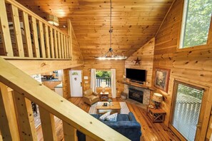 A wooden cabin interior with a living room, kitchen, and a staircase leading to an upper level. - Peaceful Log Cabin Retreat with Hot Tub (Sevierville)