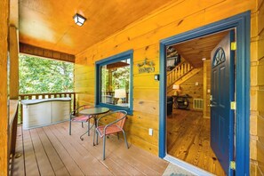 A wooden cabin with a deck, a table with chairs, and a blue door. - Peaceful Log Cabin Retreat with Hot Tub (Sevierville)