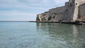 A clear coastal view with a historic stone wall and a swimmer in the water. - LA TORRETTA SHORT-TERM RENTALS (MONOPOLI)