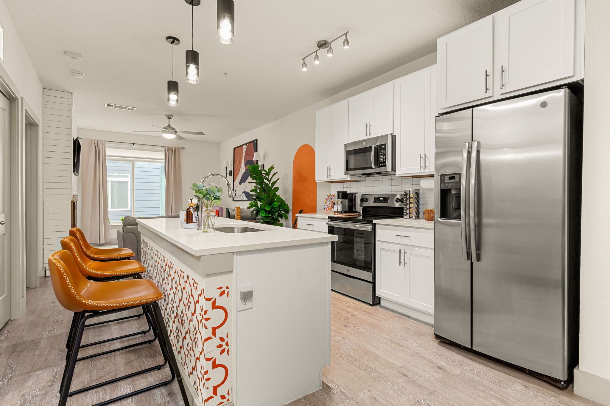 A modern kitchen with white cabinets, stainless steel appliances, and a central island with bar stools.