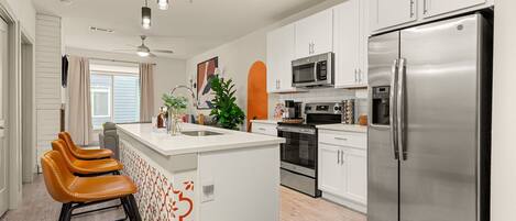 A modern kitchen with white cabinets, stainless steel appliances, and a central island with bar stools.