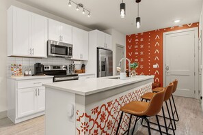 A modern kitchen with white cabinets, stainless steel appliances, and a central island with bar stools. - Downtown Suite on San Antonio Riverwalk Walkable to the Alamo (San Antonio)