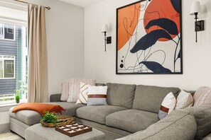 A modern living room with a grey sectional sofa, a large abstract painting, and two wall-mounted lamps. - Downtown Suite on San Antonio Riverwalk Walkable to the Alamo (San Antonio)