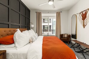 A hotel room with a bed, a chair, a bench, a ceiling fan, a large mirror, and a view of the outside balcony. - Downtown Suite on San Antonio Riverwalk Walkable to the Alamo (San Antonio)