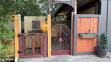 Une porte en bois avec une pancarte indiquant « BIENVENUE », une plaque portant un numéro et un pot de fleurs.