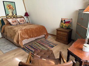 Une chambre à coucher comprenant un lit, une table de chevet en bois, une chaise, une table et une commode.