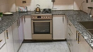 Una cuina amb armaris blancs, una cuina i un taulell.