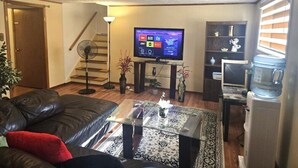A living room with a sofa, coffee table, TV, staircase, and a water dispenser.
