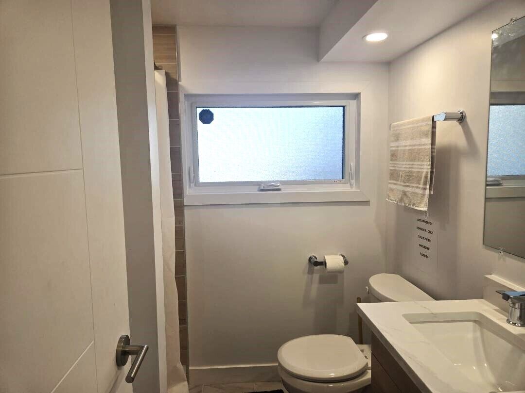 Ein Badezimmer mit Toilette, Waschbecken, Fenster und Handtuchhalter.