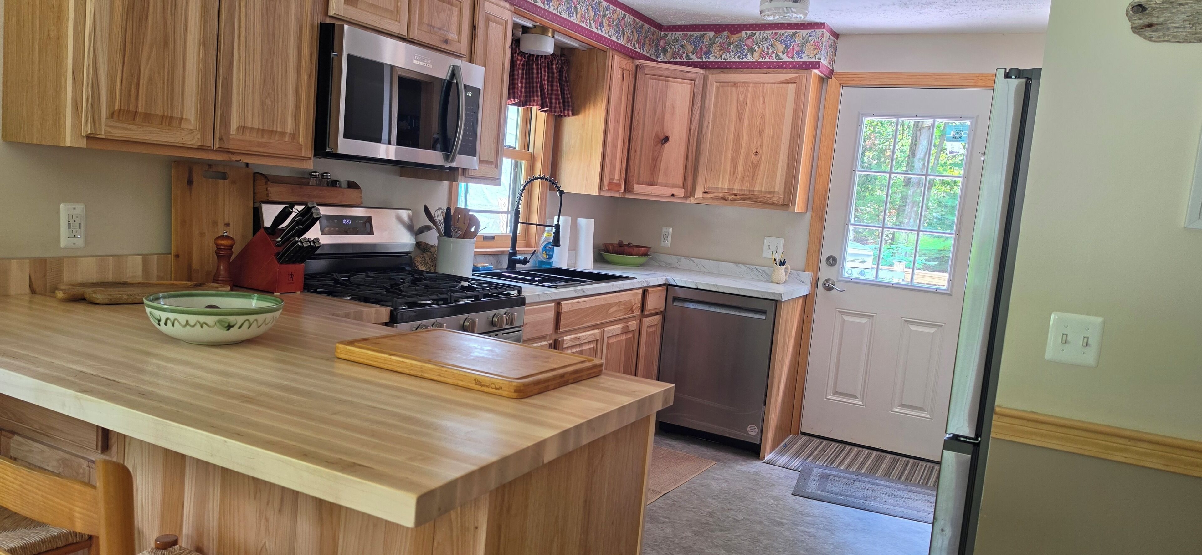 A kitchen with wooden cabinets, a microwave, stove, and a dishwasher.