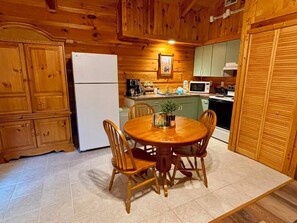 Un interior de madera con una mesa y sillas para comer, un refrigerador y un microondas.