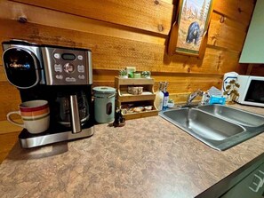 A kitchenette with a coffee maker, a microwave, a sink, and a wooden wall. - Sleeps 4, Couples Cabin, Hot Tub, Fireplace, Pet Friendly, 8.8 Mi to Gatlinburg (Gatlinburg)