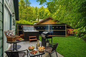 A backyard with a hot tub, grill, picnic table, and a wooden deck. - Sleeps 4, Couples Cabin, Hot Tub, Fireplace, Pet Friendly, 8.8 Mi to Gatlinburg (Gatlinburg)