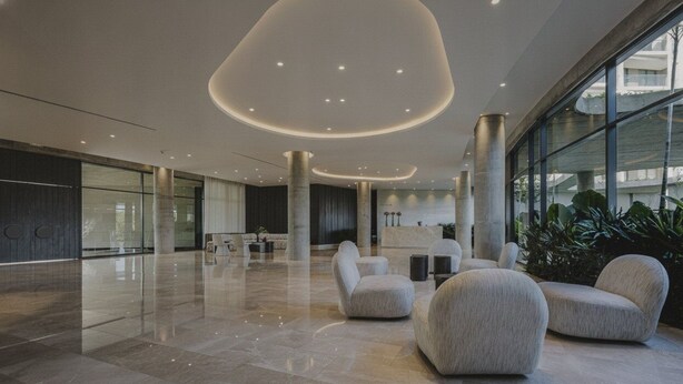 Eine moderne Lobby mit gewölbter Decke, Sitzbereichen und großen Fenstern.