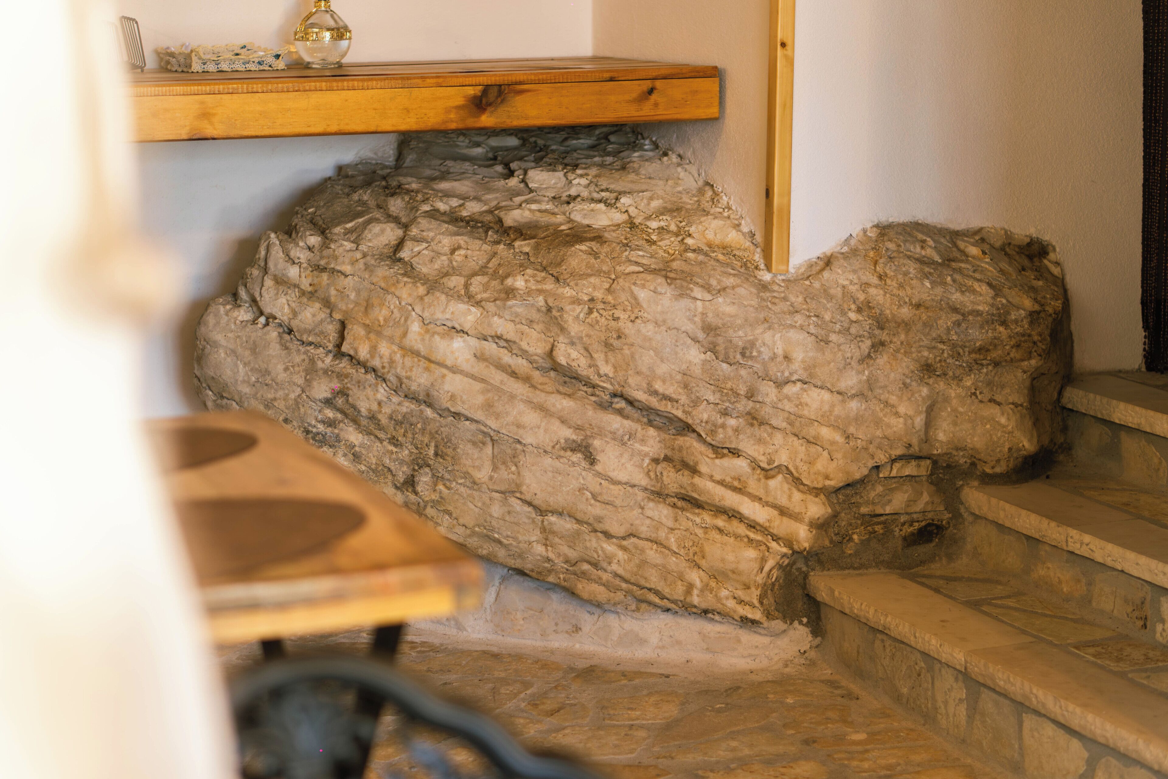 A stone wall with a wooden shelf above it.