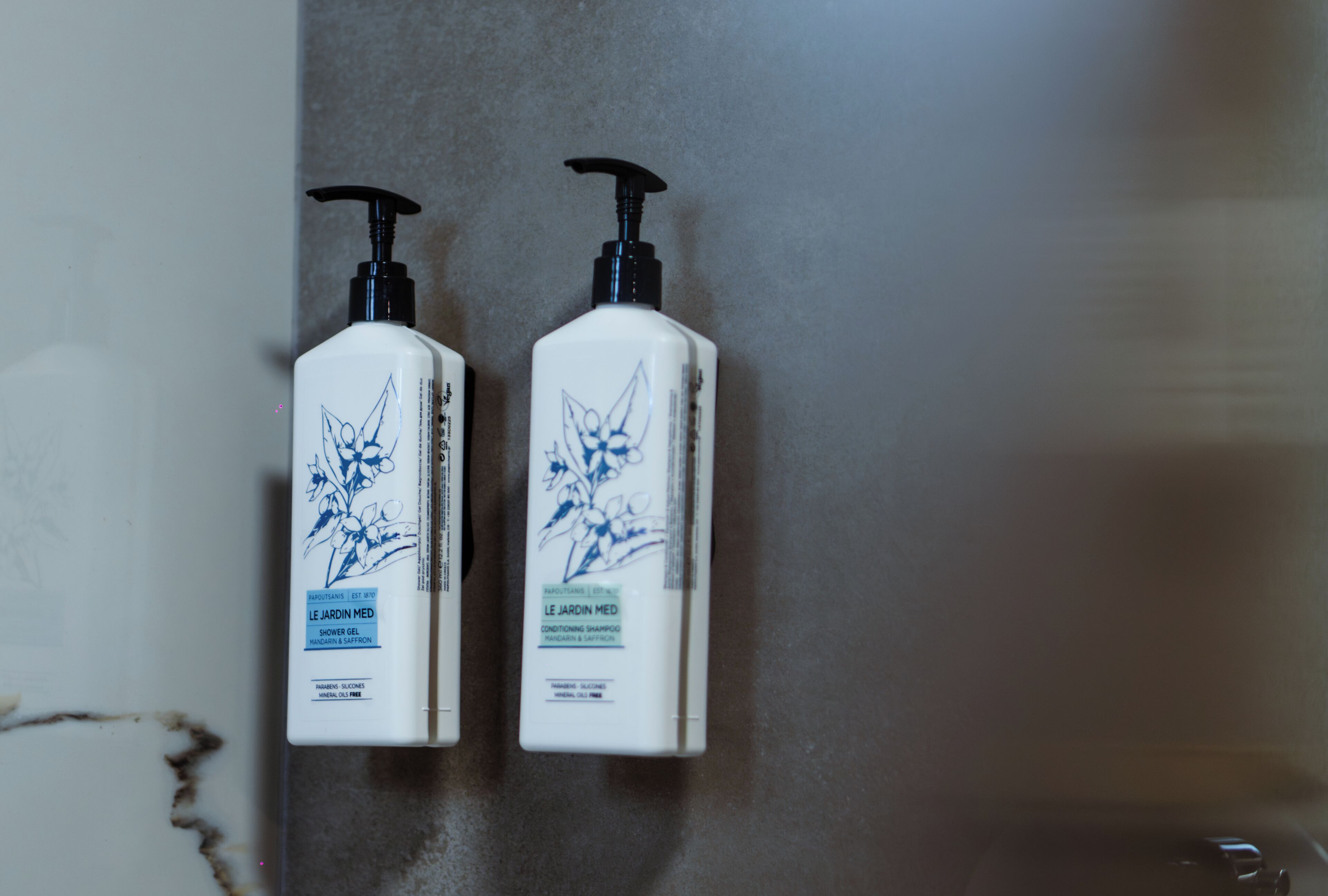 Dos botellas de gel de ducha y acondicionador champú Le Jardin Med sobre una encimera de baño.