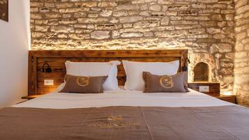 A bed with a stone wall backdrop, wooden headboard, and two pillows with a logo.