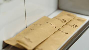 Un interior blanco con un estante de madera que contiene tres bolsas de papel marrón etiquetadas 'pentavalent kit'.