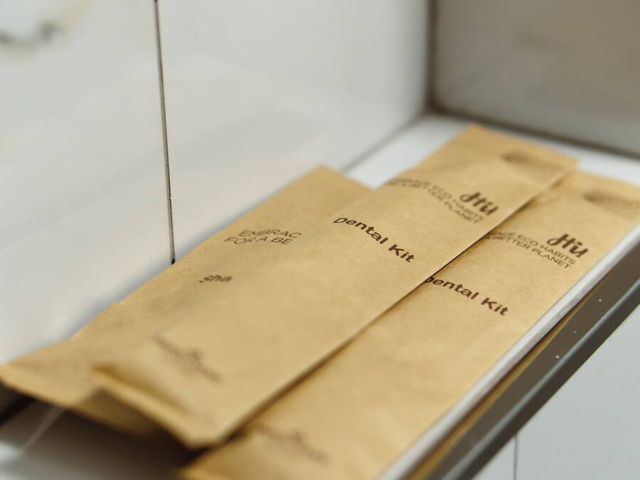 Un interior blanco con un estante de madera que contiene tres bolsas de papel marrón etiquetadas 'pentavalent kit'.