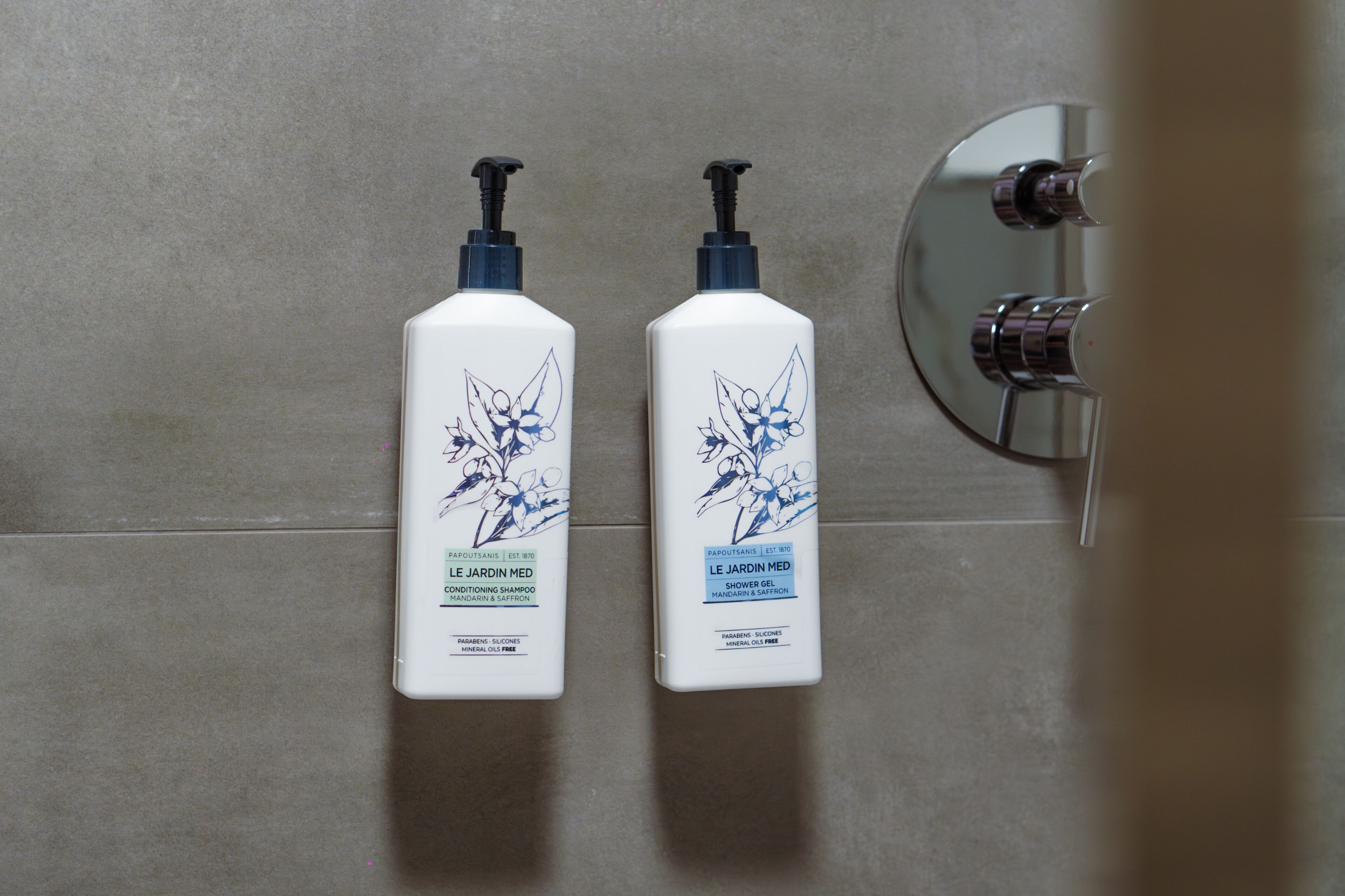 Two bottles of shower gel on a tiled wall.