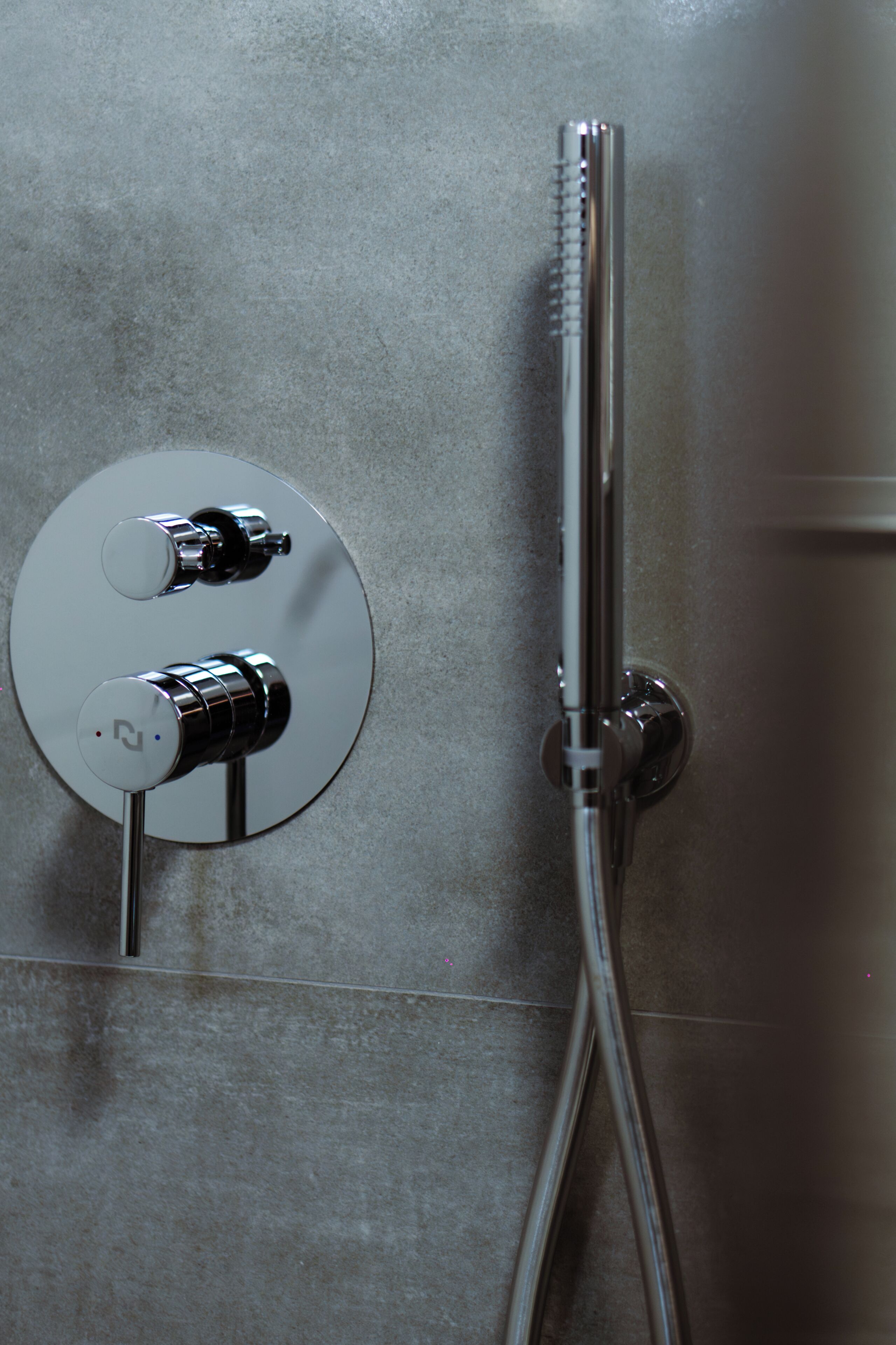 A shower with a chrome faucet and control knobs.